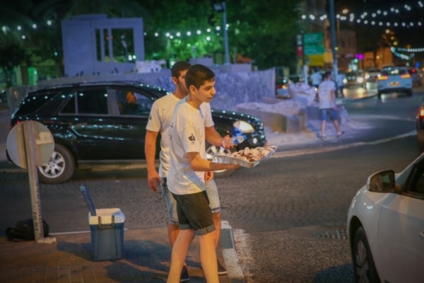 two youth group boys handing out food to muslims as they break the ramadan fast