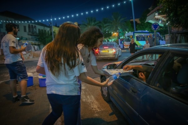 youth group girls handing out water bottles to muslim people during ramadan